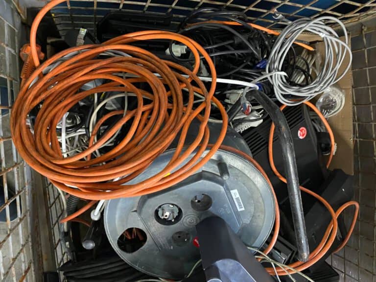 Kabel, Kabeltrommel und Elektroschrott in einer Gitterbox zur Abholung