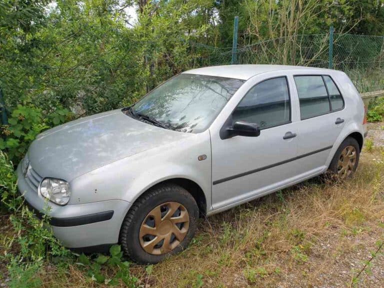 Altes Auto im Garten, das zur kostenlosen Autoverschrottung abgeholt werden soll